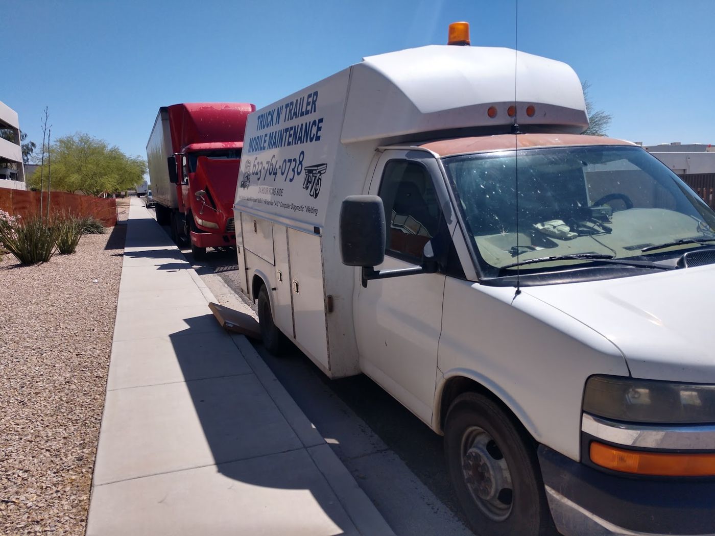 The Truck N' Trailer service van parked beside a red semi truck