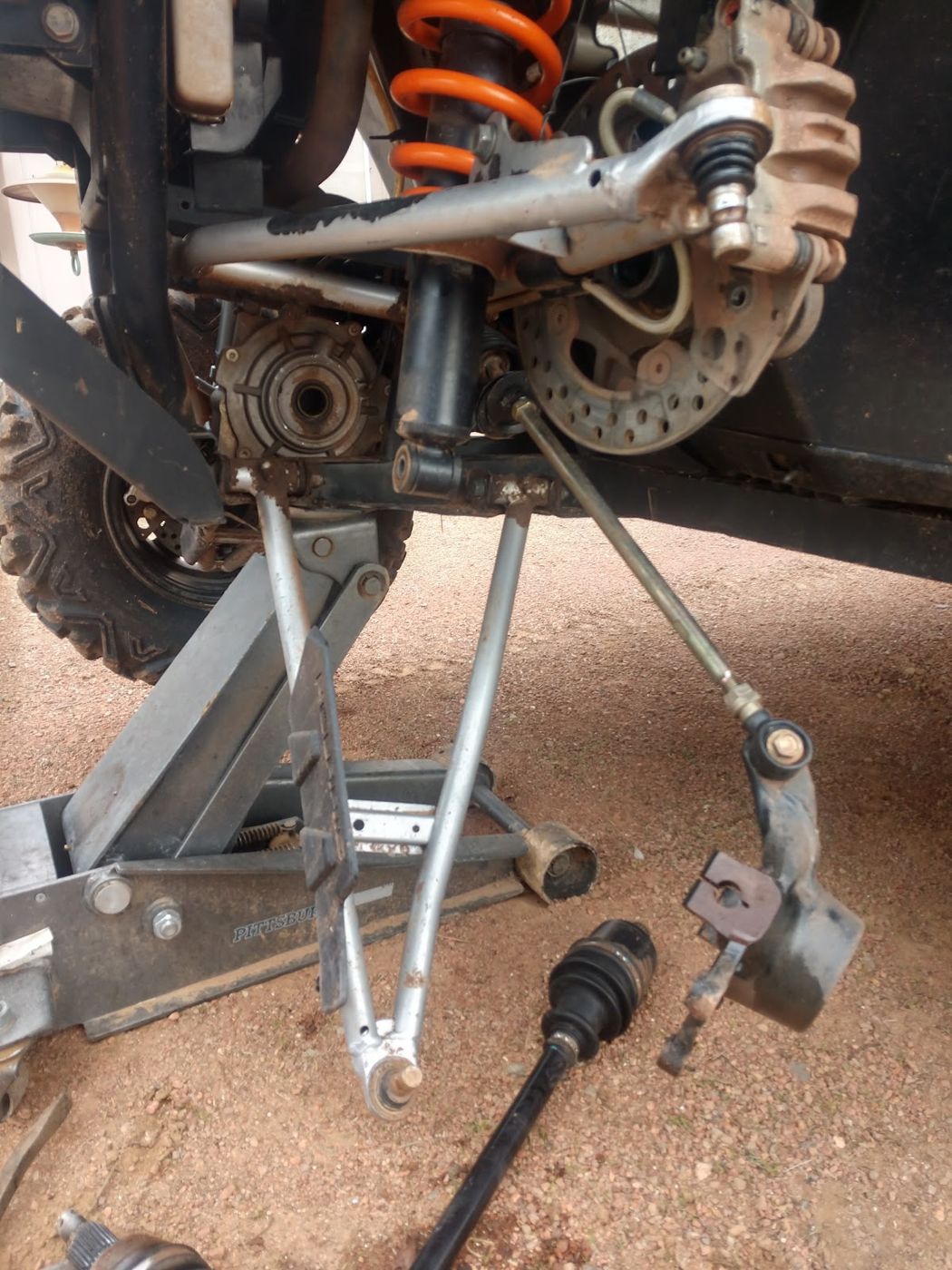A suspension arm and brake rotor on a vehicle lifted on a jack