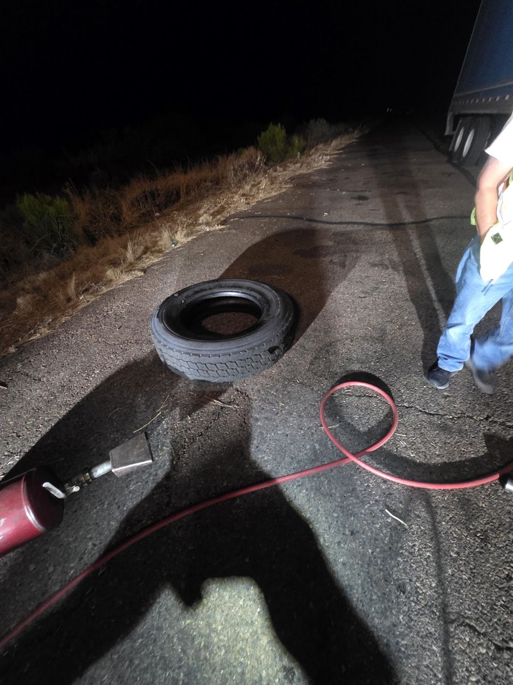 A flat tire on the ground at night under work lights