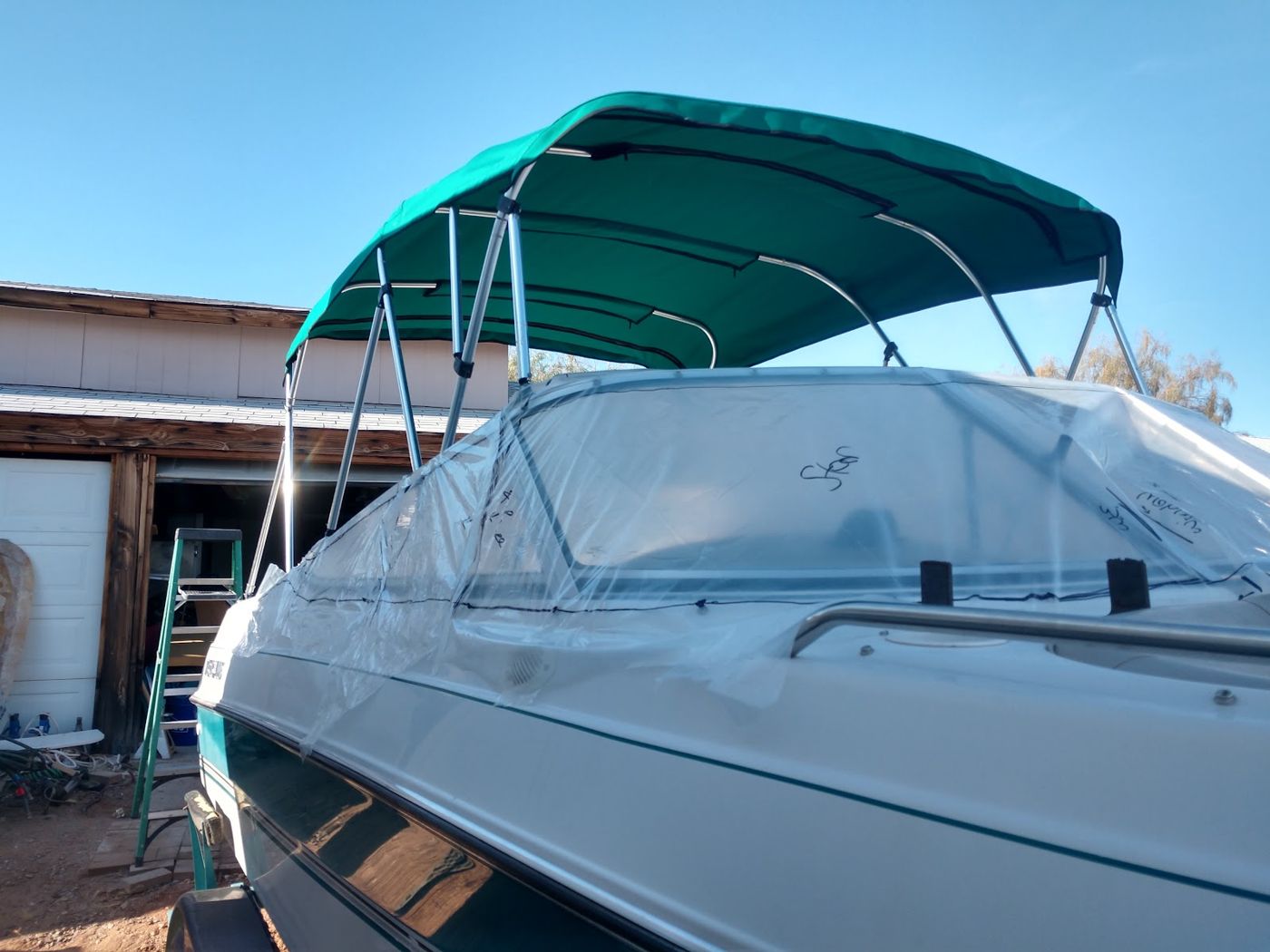 A boat on a trailer with a teal canvas top